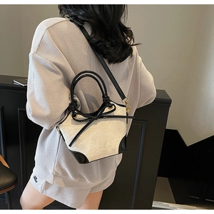 Détail du nœud contrasté sur tissu beige texturé et sac seau en cuir noir élégant