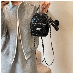 Detail view of mini black quilted patent leather backpack with gold metal chain strap