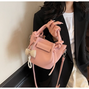 Close-up of pink litchi grain leather bucket bag with bow and pearl charms for women