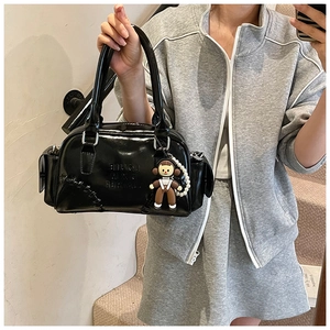 Detail of black patent leather bowling bag with cute doll charm and pearl chain decoration