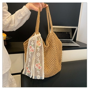 Detail of hand-woven straw tote bag with intricate floral lace ribbon and hollow mesh texture