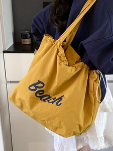 Large yellow canvas tote bag with blue Beach print and drawstring closure on shoulder