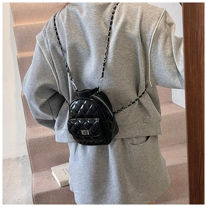 Close-up of black quilted leather mini backpack with metal chain strap and twist-lock