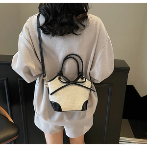 Vue détaillée du sac seau bicolore avec nœud noir et finitions dorées sur mannequin