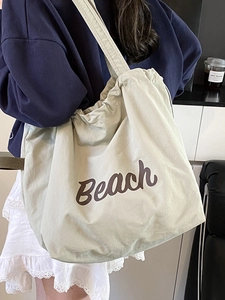 Minimalist beige canvas tote bag with brown Beach lettering print for casual travel