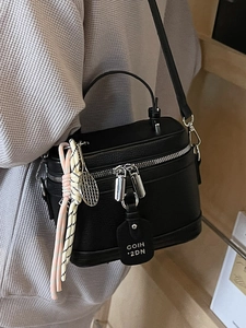 Sac bandoulière boîte noir avec texture litchi et poignée porté par un mannequin