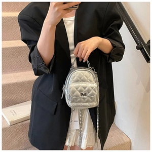 Detail of silver quilted mini backpack featuring metallic finish and metal chain straps