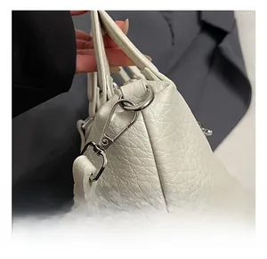 Close-up of premium silver-tone hardware and lobster clasp on white lychee leather bag