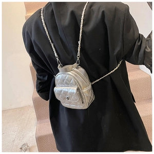 Detail of silver quilted mini backpack with metallic PU leather and chain straps on model