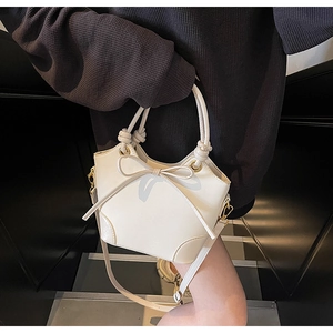 Détail du sac seau crème avec nœud décoratif et bandoulière réglable pratique