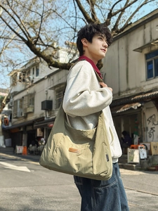 Detail of adjustable strap and brown logo patch on large canvas messenger tote bag