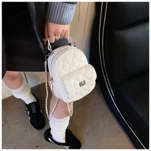 Macro detail of white quilted mini backpack with shiny finish and silver metal lock