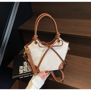 Vue détaillée des coutures contrastées et du nœud doré élégant sur le sac seau chic