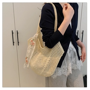 Close-up of woven tote bag with hollow grid pattern and floral embroidered lace scarf