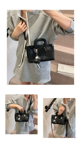 Detail view of black lychee leather handbag with silver heart charm and round top handles