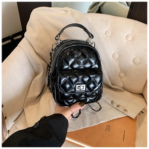 Detail of black quilted backpack with silver clasp and leather-interwoven chain strap
