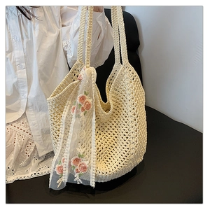 Detail of hollow woven tote bag with pink floral lace scarf on white lace dress background