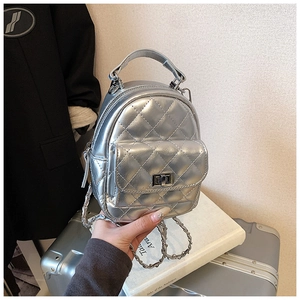 Detail of silver quilted mini backpack featuring metallic chain straps and turn-lock closure