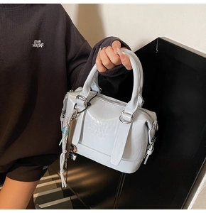 Detail of light blue embossed leather Boston bag with metallic buckle and charms