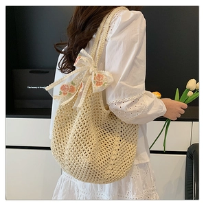 Close-up of beige woven tote bag featuring an orange flower embroidery on a white organza bow