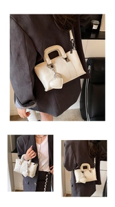 Detail of cream white textured faux leather handbag with heart-shaped pendant and strap