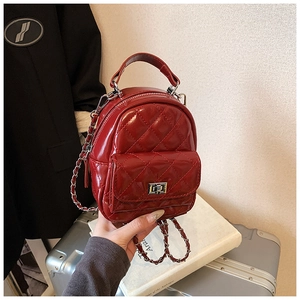 Detailed shot of red quilted mini backpack with glossy finish and silver chain straps