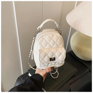 Close-up of white quilted leather texture with metal twist lock and chain strap detail