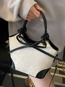 Sac seau contrasté en toile beige et cuir noir avec un détail de nœud élégant