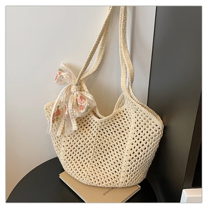 Detail of beige crochet tote bag featuring delicate organza bow with floral embroidery