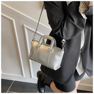 Detail view of a silver metallic crossbody bag styled with a professional black blazer
