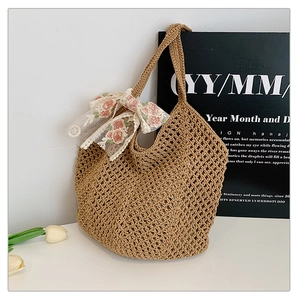 Detailed close-up of woven tote bag featuring white lace bow and pink floral embroidery