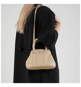 Litchi texture beige handbag shown over a black coat to highlight the leather details