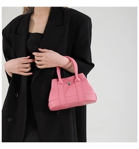 Detailed view of pink lychee leather texture and silver metal buckle on a tote bag
