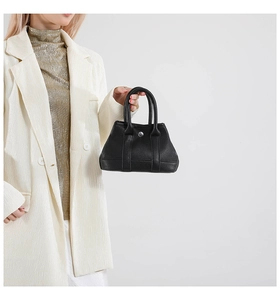 Close-up of black lychee grain leather handbag with silver round buckle and top handle
