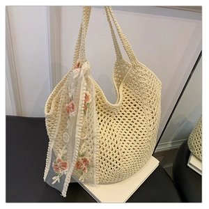 Macro detail of cream crochet tote bag with openwork diamond knit and floral lace scarf