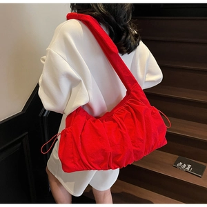 Detalle del bolso de hombro de nailon rojo plisado con cordones sobre una modelo