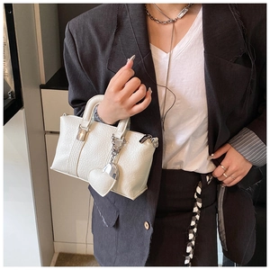 Detail of white lychee leather texture on Boston bag with silver heart charm