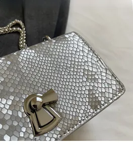Detail of silver fish-scale texture leather bag featuring a bow-shaped metal clasp