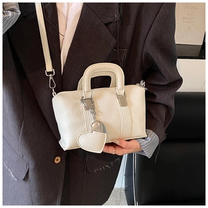 Detail showing white litchi pattern PU leather handbag with a heart-shaped charm accessory