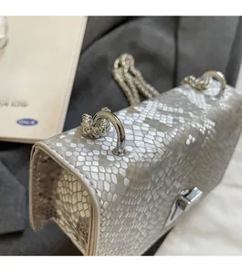 Detail shot of silver faux leather square bag featuring snake scale texture and metal chain