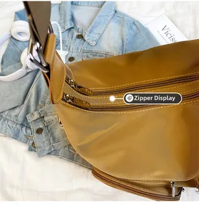 Khakifarbene Nylontasche mit braunem Gurt und Doppelreißverschluss im Detail