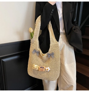 Detail der Strohtasche mit süßen Plüschbären und Gingham-Schleifen auf gewebter Textur