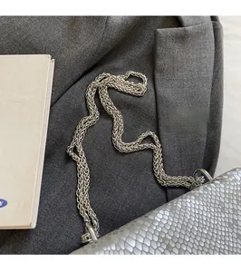 Detail of silver woven chain strap and snakeskin texture on a modern small square bag
