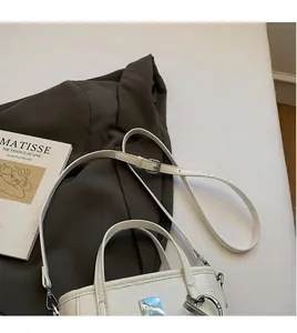 Dettaglio borsa a secchiello in pelle verniciata bianca con finiture argentate e tracolla