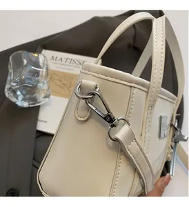 Dettaglio della borsa a secchiello bianca in pelle lucida con fibbie metalliche argento