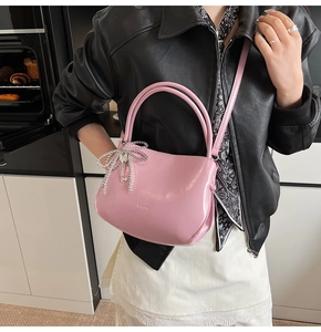 Detail of pink PU leather bucket bag with silver bow charm and branded embossed logo