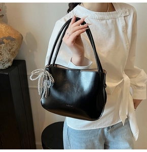 Close-up of black PU bucket bag with silver beaded bow charm and dual top handles