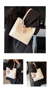 Close-up of creamy white tote bag featuring a cute pink plush bear charm and sleek leather