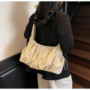 Primer plano detallado de un bolso nube plisado beige con cordón ajustable en el lateral