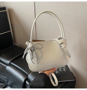 Detail view of white PU leather bucket bag with silver bead bow and heart key charm